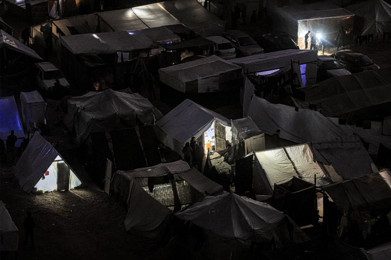 The tent camps of displaced Palestinians are pictured in Rafah in the southern Gaza Strip close to the border with Egypt after sunset on December 31, 2023 amid the ongoing conflict between Israel and the militant group Hamas. (Photo by AFP)