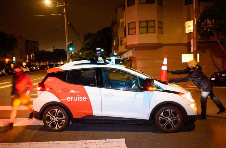 (FILES) Members of SafeStreetRebel, a group of anonymous anti-car activists, place a cone on a self-driving robotaxi to disable it in San Francisco, California on July 11, 2023. California authorities on October 24, 2023 suspended testing of Cruise driverless cars put to work in the US state as robotaxis by General Motors, citing safety concerns following a series of accidents and other problems. (Photo by Josh Edelson / AFP)