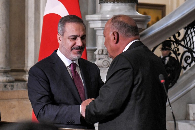 Egypt's Foreign Minister Sameh Shoukry (R) and Turkey's Foreign Minister Hakan Fidan shake hands after a joint press conference in Cairo on October 14, 2023. (Photo by Ahmed HASAN / AFP)