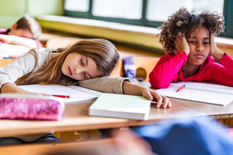 Tired schoolgirls feeling bored on a class at elementary school.