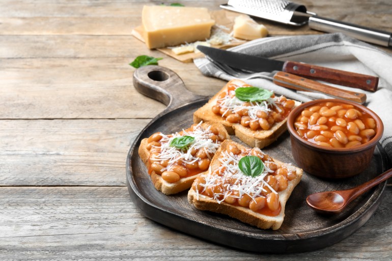 Toasts with delicious canned beans on wooden table, space for text