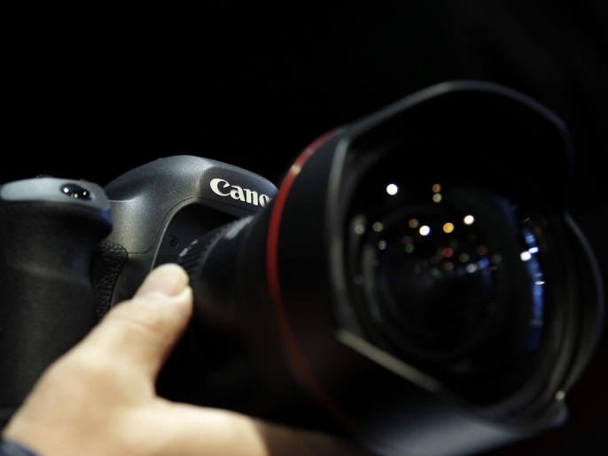 An attendee tries out a Canon Inc. EOS-5Ds digital single lens reflex (DSLR) camera mounted with an EF 11-24mm f/4L USM ultra-wide zoom lens at the CP+ Camera and Photo Imaging Show in Yokohama, Kanagawa Prefecture, Japan, on Thursday, Feb. 12, 2015. The largest camera and photo imaging show in Japan, hosted by the Camera & Imaging Products Association, runs through Feb. 15.