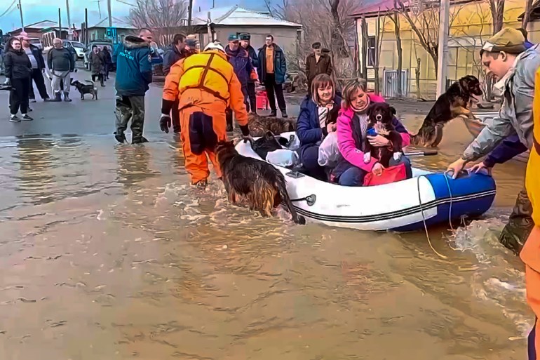 In this image taken from a video released by the Russian Emergency Ministry Press Service on Saturday, April 6, 2024, emergency workers evacuate local residents with their pets after a part of a dam burst causing flooding, in Orsk, Russia. Floods hit a city in the Ural Mountains areas after a river dam burst there, prompting evacuations of hundreds of people, local authorities said. The dam breach in Orsk, a city less than 20 kilometers north of Russia's border with Kazakhstan, occurred on Friday night, according to Orsk mayor Vasily Kozupitsa. (Russian Emergency Ministry Press Service via AP)