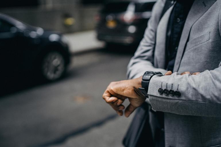 Faceless African American entrepreneur looking at wristwatch