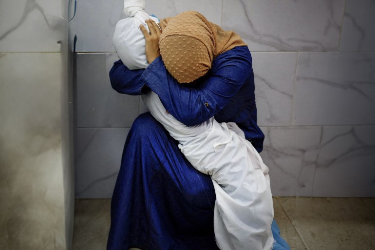 [1/15]In a final embrace Inas Abu Maamar, 36, cradles the shroud-wrapped body of her five-year-old niece, Saly, who died in Israeli strikes on Khan Younis, at the Nasser Hospital morgue before her funeral in southern Gaza, October 17, 2023. REUTERS/Mohammed Salem KHAN YOUNIS, PALESTINIAN TERRITORIES