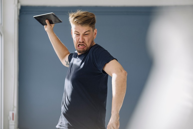 Angry man throwing tablet away