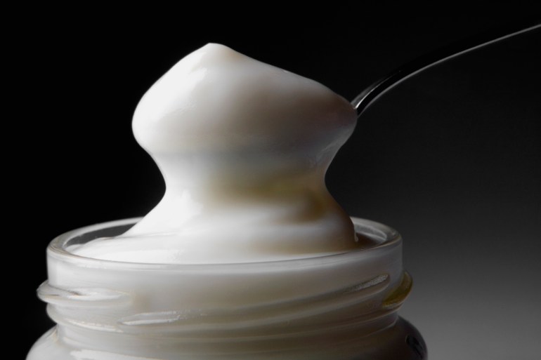 Close-up of a spoon in a jar full of mayonnaise - stock photo