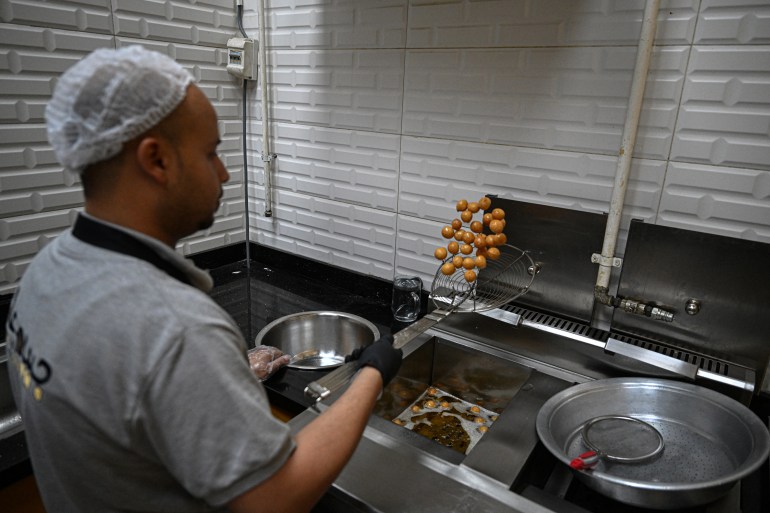 An employee fries sweet pastry with traditional Sudanese taste at a restaurant run by a businessman who relocated to Cairo after fleeing the ongoing war in Sudan, on May 27, 2024. - Across the sprawling megalopolis of Cairo, home to 20 million people, many Sudanese refugees have opened businesses, bringing a taste of home and hoping to make a name for themselves. (Photo by Khaled DESOUKI / AFP)