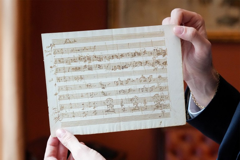 A person holds a rare autograph music manuscript by Wolfgang Amadeus Mozart, رويترز