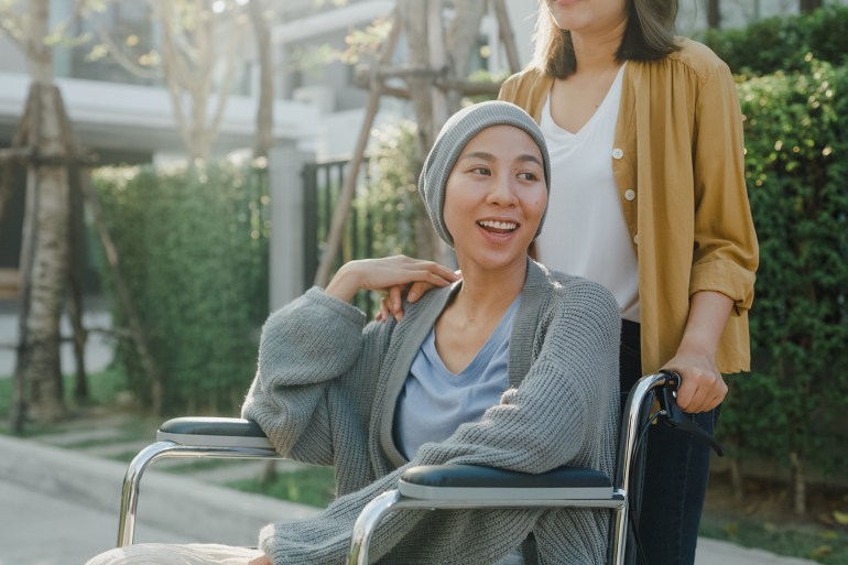 Young Asian people taking care health help cancer patients sitting in wheelchair outside home. Healthcare concept.