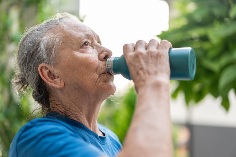 Senior woman staying fit, drinking outdoors