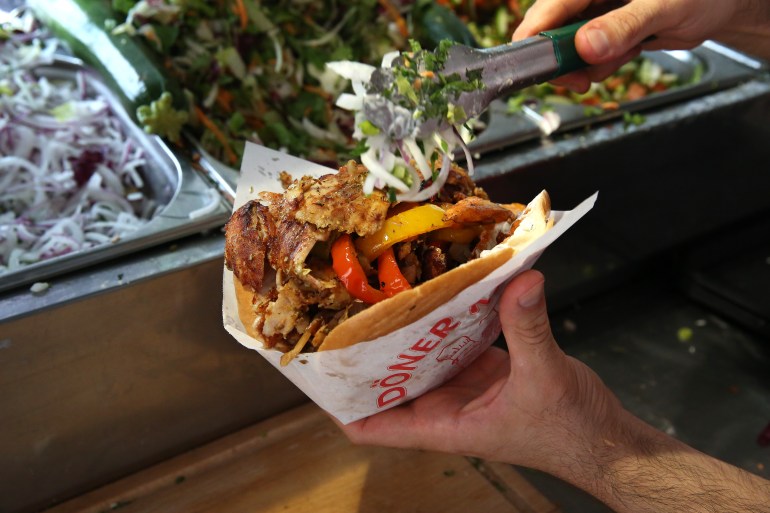 BERLIN, GERMANY - JULY 06: An employee prepares a customer's order at Mustafas Gemüse Kebap on July 06, 2022 in Berlin, Germany. The döner kebab, a fast food sandwich made of stacked, seasoned meat turned on a rotisserie, was popularized in Germany in the early 1970s by Turkish guest workers (Gastarbeiter in German, or migrants arriving in Germany after World War II to counter labor shortages), with more stands offering the dish in Berlin than in Istanbul, and many considering it to be Germany's national dish. (Photo by Adam Berry/Getty Images)