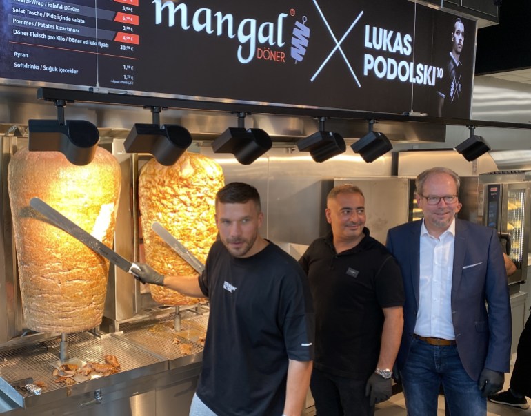 German footballer Lukas Podolski opens the 11th branch of his chain Doner Kebab restaurant in Cologne- - COLOGNE, GERMANY - JUNE 30: German footballer Lukas Podolski (L), who plays as a forward for Turkish team Antalyaspor, poses for a photo with a doner knife with his Turkish co-partner Metin Dag (2nd L) as they open up the 11th branch of their chain Doner Kebab restaurant named "Mangal Doner" in Bergheim town of Cologne, Germany on June 30, 2021. Bergheim Mayor Volker Miesseler (R) also attended the opening of the restaurant.