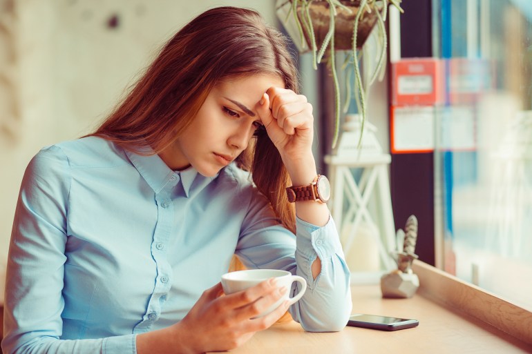 Stress. Portrait stressed sad young woman with coffee cup sitting in a trendy cafe coffee shop about to cry. City urban life style stress. Negative human emotion face expression body language attitude; Shutterstock ID 680916895; purchase_order:ajplusesp; job:; client:; other: